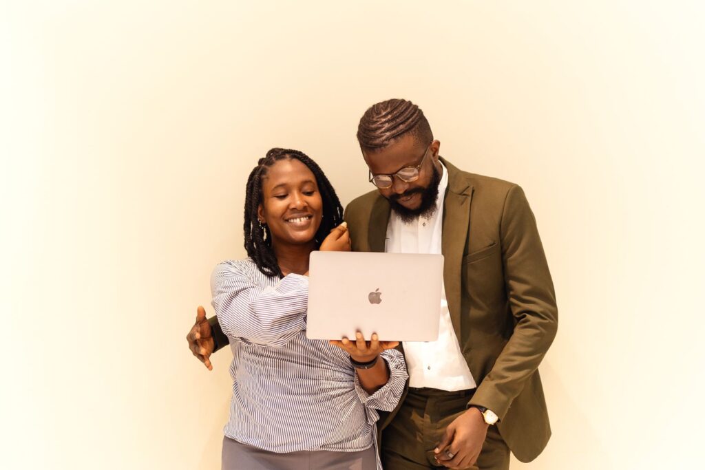 Two African colleagues smiling while collaborating on a laptop